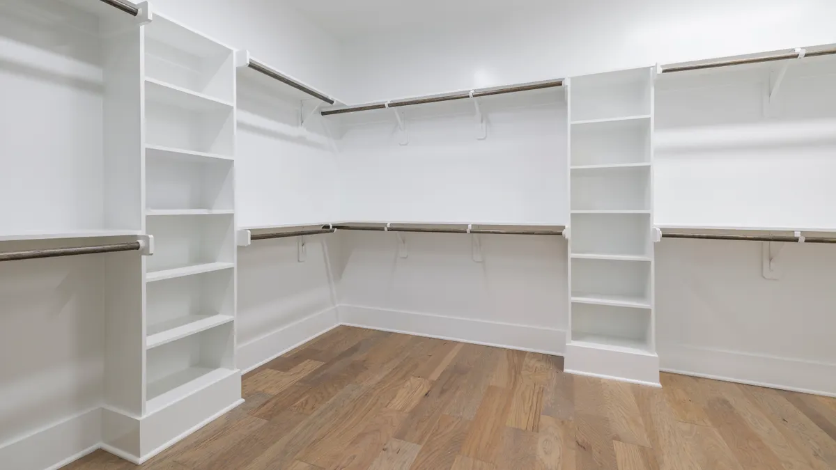 Large empty walk-in closet with shelves and hanging rods